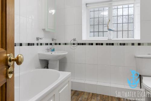 a white bathroom with a sink and a toilet at Sam Bs in Brixham