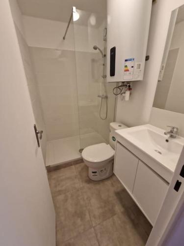 une salle de bain blanche avec des toilettes et un lavabo dans l'établissement Appartement avec accès piscine, proximité mer, au Grau-du-Roi