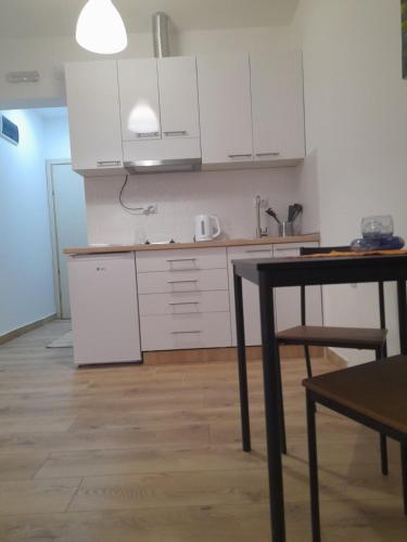 a kitchen with white cabinets and a table in a room at V & V Studio Apartments in Niš