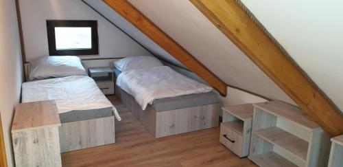 a attic room with two beds and a window at Uroczysko Trzcińsko in Trzcińsko