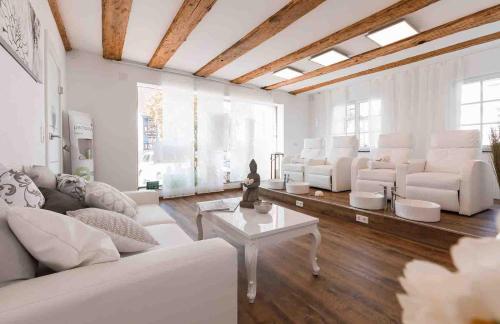 a living room with white couches and a table at Bodensee Hotel Storchen in Uhldingen-Mühlhofen