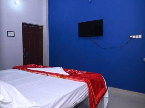 1 dormitorio con 1 cama con pared azul y TV en OYO Home Om Shanti Palace en Ayodhya