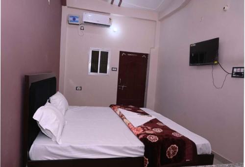Dormitorio pequeño con cama y TV en OYO Home Om Shanti Palace en Ayodhya