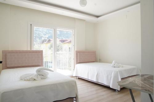 two beds in a white room with a window at golden sand sarıgerme in Dalaman