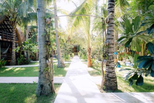 a path through a palm tree lined yard at Island View Bar & Bungalow in Gili Air