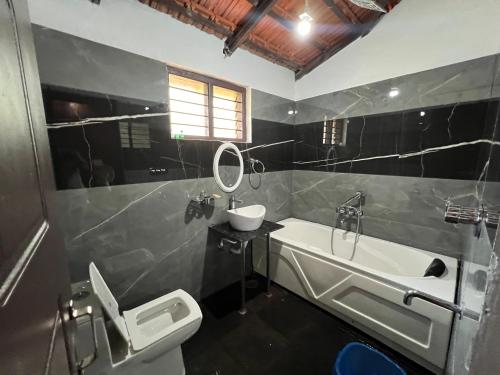 a bathroom with a sink and a toilet and a tub at Stillwater Homestay in Chikmagalūr