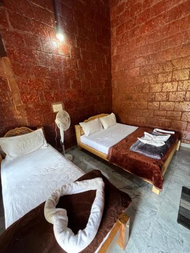 two beds in a room with a brick wall at Stillwater Homestay in Chikmagalūr