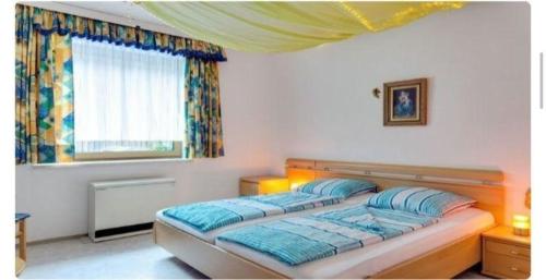 sypialnia z łóżkiem z niebieskimi poduszkami i oknem w obiekcie Ferienwohnung in Ulrichsberg w mieście Ulrichsberg