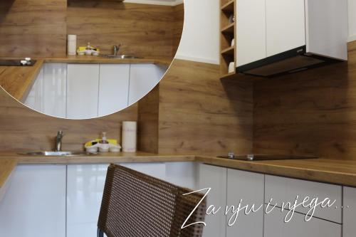 uma cozinha com armários brancos e um espelho em West Wing - Apartmani Živinice em Živinice