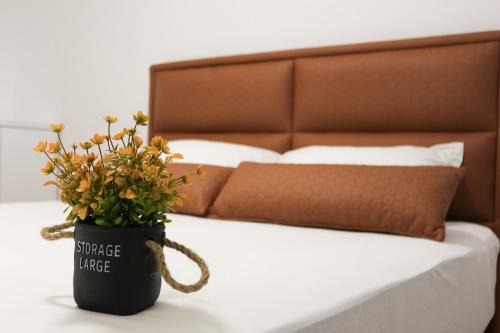 um vaso de flores sentado numa mesa ao lado de uma cama em West Wing - Apartmani Živinice em Živinice