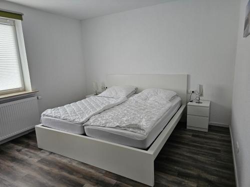 a white bedroom with a bed and a window at Fewo Minsen in Wangerland