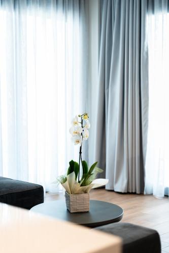 a vase with white flowers on a table in a room at Volos Inn Hotel in Volos