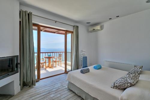 1 dormitorio con 1 cama y balcón en Villa Madouri 5 bed seafront villa with private pool, en Pogoniá