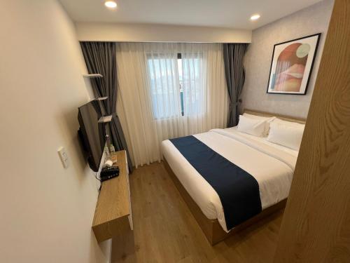 une chambre d'hôtel avec un lit et une télévision dans l'établissement Phương Mai Hotel Đà Lạt, à Đà Lạt