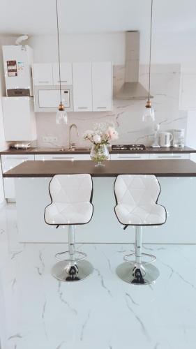 a kitchen with two white chairs and a counter at Private Pool House by Olivujoj - Your slice of paradise for six in Anavissos