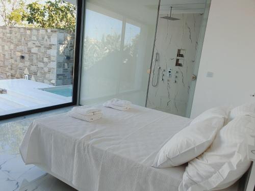 ein weißes Schlafzimmer mit einem Bett und einem großen Spiegel in der Unterkunft Two Bedroom Pool House by Olivujoj in Anavyssos