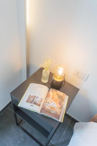 a table with a book and a vase of flowers on it at Cozy Nest on the lake by Rent All Como in Tremezzo