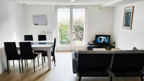 - un salon avec une table, des chaises et une télévision dans l'établissement Appartement cosy 2 chambres avec jardin, à Les Ponts-de-Cé