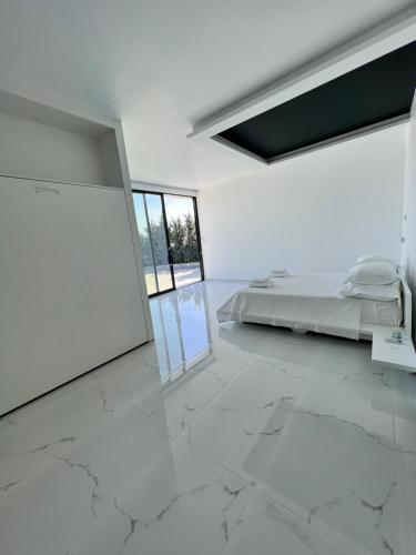 a white bedroom with a bed in a room with marble floors at Private Pool House by Olivujoj - Your slice of paradise for six in Anavissos