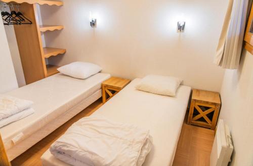 two beds in a small room with wooden floors at Résidence Le Parc Des Airelles - 2 Pièces pour 6 Personnes 474 in Les Orres