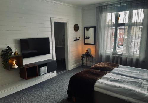a bedroom with a bed and a flat screen tv at Telegrafen Lägenhetshotell in Sveg