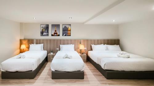 two beds in a hotel room with white sheets at indigo Hotel Hatyai in Ban Kohong