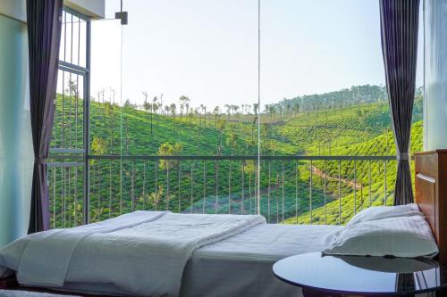 - une chambre avec un lit et une grande fenêtre avec vue dans l'établissement Zen Vista, à Valparai