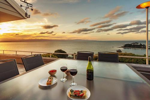 a table with two glasses of wine and a view of the ocean at Aquavista - Beautiful Views over Tasman Bay in Nelson