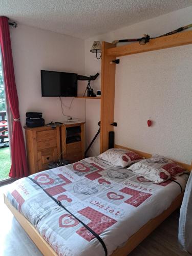 - une chambre avec un lit avec un cadre en bois et une télévision dans l'établissement Appartement Montagnard Serre-Chevalier., à Saint-Chaffrey