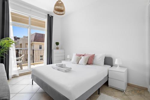 a white bedroom with a large bed and a balcony at WelHome - Serene Bliss: Regent House 2 Studio Haven in Dubai