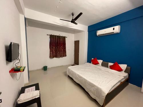 ein Schlafzimmer mit einer blauen Wand und einem Bett mit roten Kissen in der Unterkunft Hotel Kings Inn in Nagpur