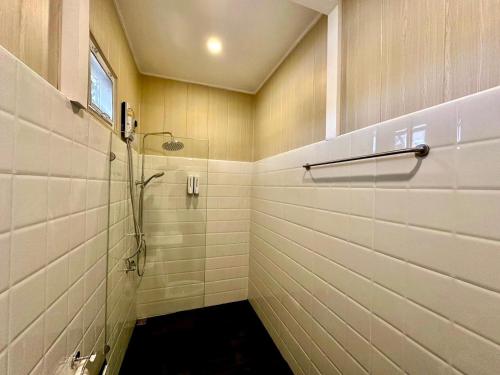 y baño con ducha y paredes de azulejos blancos. en อาลาแคมป์, en Ban Mo Maklua