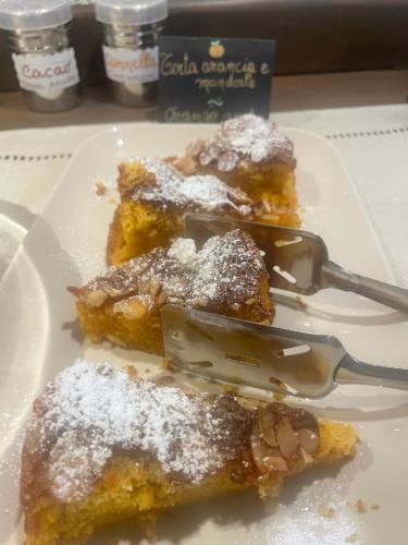 a plate with three pieces of food with powdered sugar at B&B Il Castellaccio - Albavilla in Albavilla