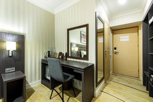 a dressing room with a desk and a mirror at Shymkent Grand Hotel in Shymkent