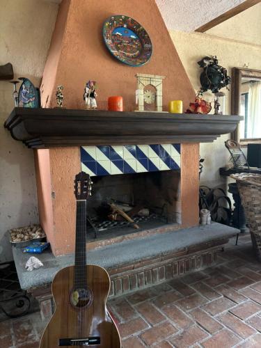 a guitar in a living room with a fireplace at Cabaña de descanso "El Tigre" in Quiroga