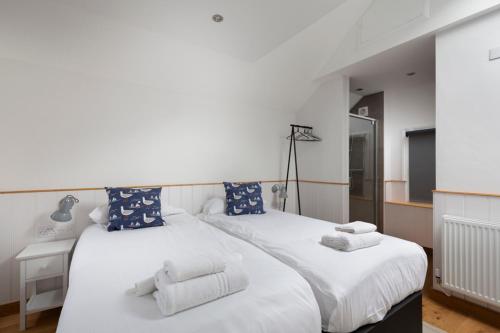 a bedroom with a large white bed with blue pillows at Stag Cottage, Sea wall in Whitstable