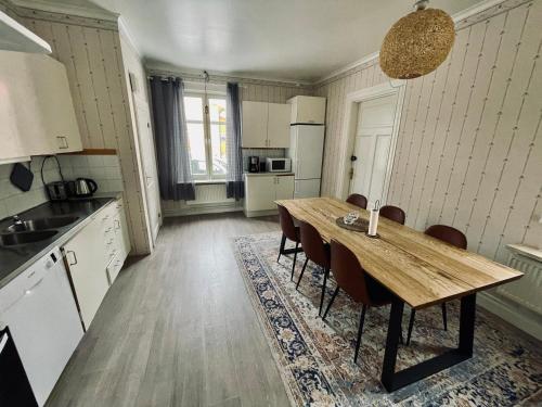 a kitchen with a wooden table and chairs in it at Telegrafen Lägenhetshotell in Sveg