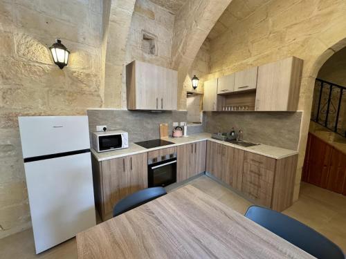 a kitchen with a white refrigerator and a table with chairs at The Nest 148 Townhouse in Għajn il-Kbira