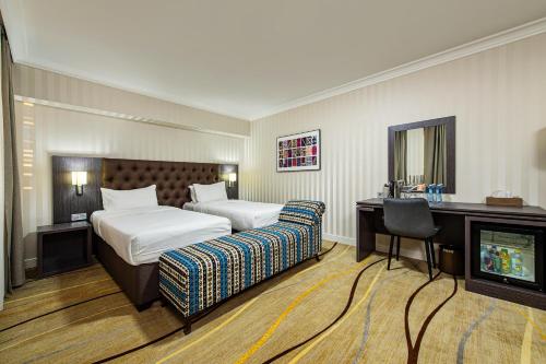 a hotel room with two beds and a television at Shymkent Grand Hotel in Shymkent