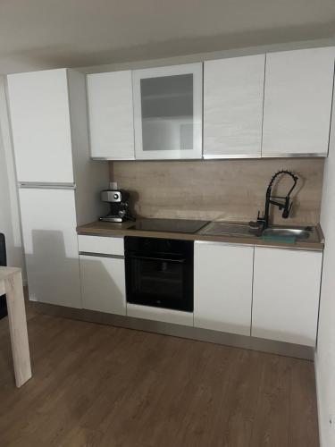 uma cozinha com armários brancos e um lavatório preto em Appartement de vacances em Fillinges