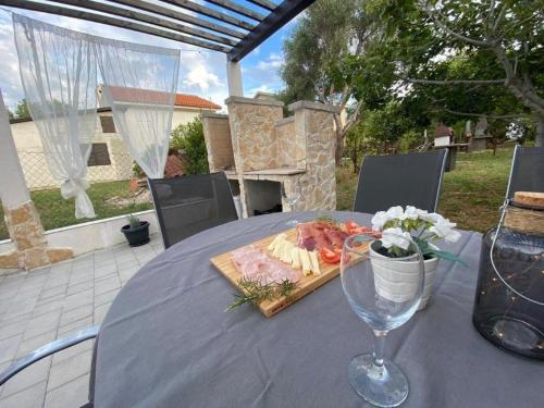 Wohnung in Privlaka mit Terrasse, Grill und Garten في بريفلاكا: طاولة مع طبق من الطعام وكأس من النبيذ
