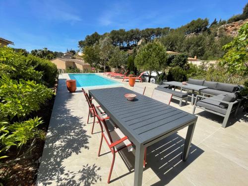 drewniany stół i krzesła przy basenie w obiekcie Belle villa provençale avec piscine privée w mieście Carqueiranne