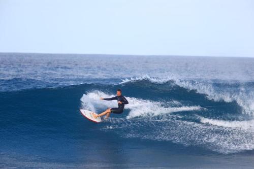 a man riding a wave on a surfboard in the ocean at Private surf house & garden, v near beach & town in Santa Maria