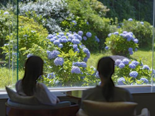 two women sitting in chairs looking out a window at flowers at Kamakura Prince Hotel in Kamakura