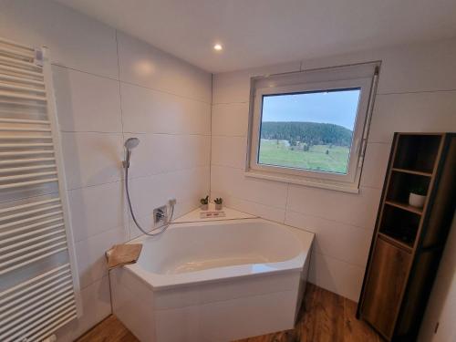 una vasca bianca in un bagno con finestra di Deluxe Ferienwohnung Schwarzwald, 8 Personen, 140 qm, Haus Sonnenschein a Todtnau