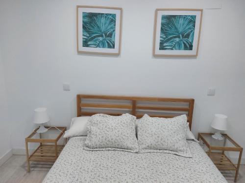 ein Schlafzimmer mit einem Bett mit zwei Bildern an der Wand in der Unterkunft Los Pinos 8 in Benahavís