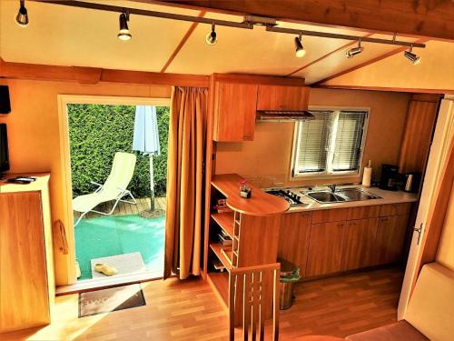 スロヴェニ・グラデツにあるEin Mobilheim in einer grünen und waldreichen Umgebungのキッチン(シンク、コンロ付)、窓が備わります。