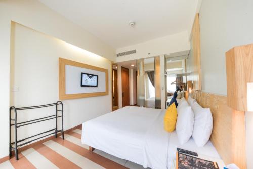 1 dormitorio con 1 cama blanca grande con almohadas en The ONE Legian, en Legian