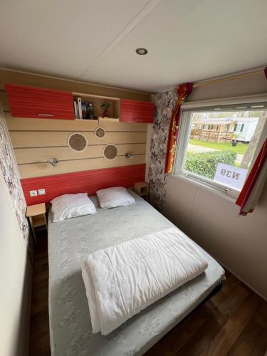 une petite chambre avec un lit et une fenêtre dans l'établissement Mobilhome 3 chambres, à Boofzheim