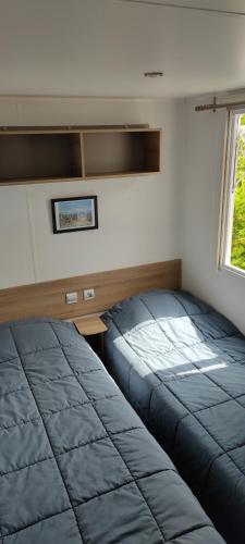 une chambre avec deux lits et un bureau et une fenêtre dans l'établissement Mobil Home tout confort aux Charmettes, aux Mathes